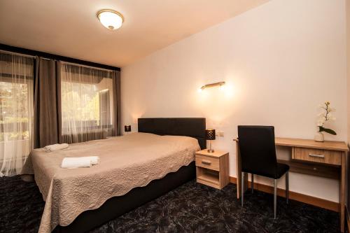 a bedroom with a bed and a desk and a window at Hotel Faraon in Celje