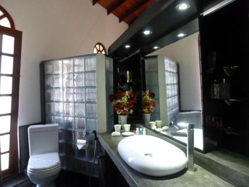 a bathroom with a toilet and a sink and a tub at Ayubowan Swiss Lanka Bungalow Resort in Bentota