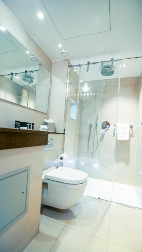 a white bathroom with a toilet and a shower at Blakemore Hyde Park in London