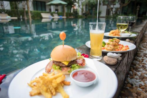 a table with a sandwich and french fries and a glass of beer at Tanei Angkor Resort and Spa in Siem Reap