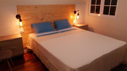 a large white bed with two blue pillows on it at BRUMA HOSTEL in Ponta Delgada