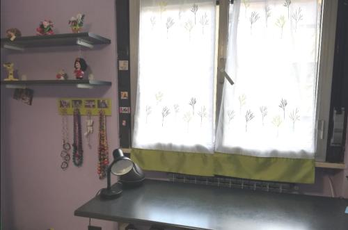 a desk in front of a window with a green curtain at Le stanze di Linda in Coppito