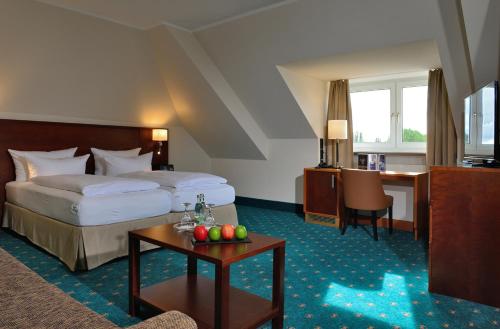 ゴータにあるHotel Der Lindenhofのベッドとリンゴ付きのテーブルが備わるホテルルームです。