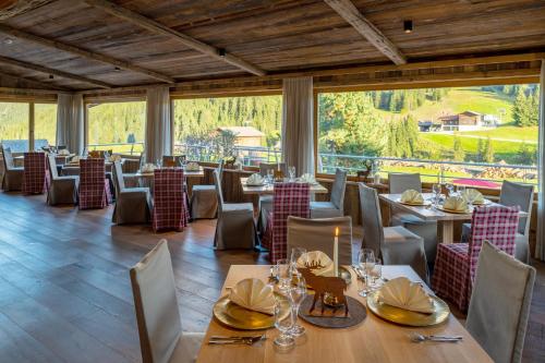 ein Restaurant mit Tischen und Stühlen und einem großen Fenster in der Unterkunft Saltria - your Alpine experience in Alpe di Siusi