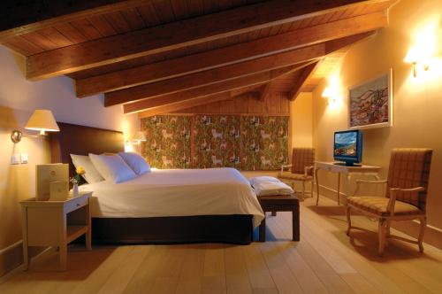 a bedroom with a large bed and a television in it at Santa Marina Arachova Resort & Spa in Arachova