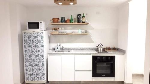 Una cocina blanca con refrigerador y microondas. en Bariloche Apart, en San Carlos de Bariloche