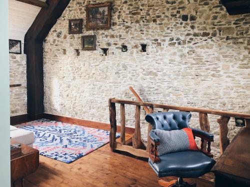 a living room with a chair and a brick wall at Glatigny Farmhouse - close to beach - proche de la plage in Glatigny