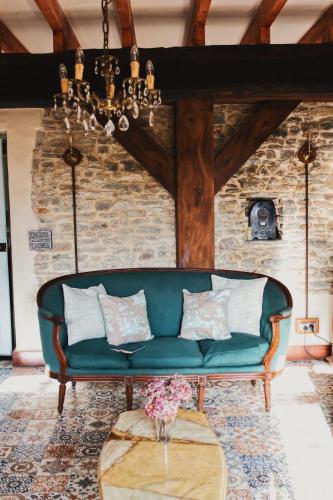 a green couch in a room with a stone wall at Glatigny Farmhouse - close to beach - proche de la plage in Glatigny