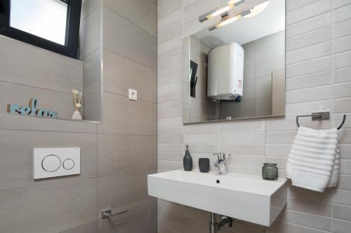 a bathroom with a white sink and a mirror at Villa Four Brothers - Middle Floor in Podstrana