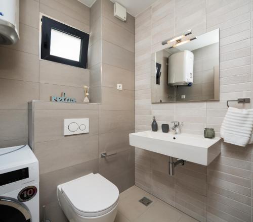 a bathroom with a white toilet and a sink at Villa Four Brothers - Middle Floor in Podstrana