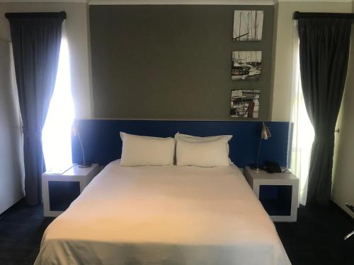 a bedroom with a large white bed with two windows at Premier Splendid Inn Bayshore in Richards Bay