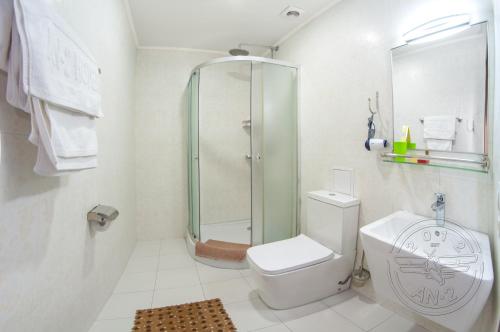 a white bathroom with a shower and a toilet at Antwo-Hotel in Kharkiv