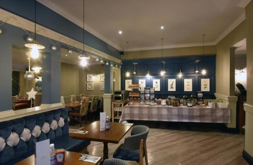 uma sala de jantar com mesas e cadeiras e um balcão em Waterside by Greene King Inns em Warrington