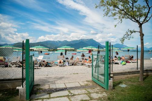 a group of people sitting on a beach near the water at Camping Baia Verde in Manerba del Garda