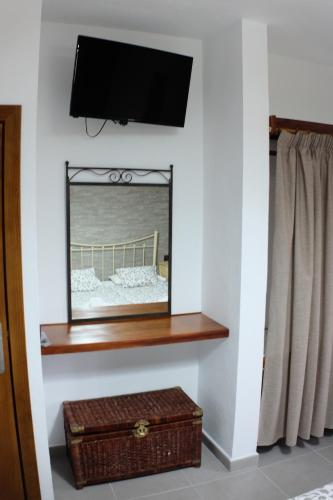 a mirror on a wall with a shelf and a television at Apartamentos Finca Wapa in Frontera