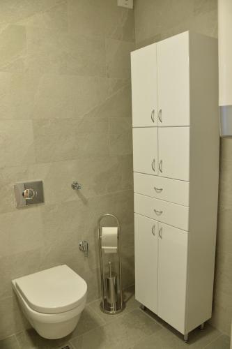 ein Bad mit einem WC und einem weißen Schrank in der Unterkunft Pupin Palata business apartman B5 in Novi Sad