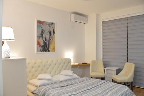 ein Schlafzimmer mit einem Bett und zwei Stühlen und einem Schreibtisch in der Unterkunft Pupin Palata business apartman B5 in Novi Sad