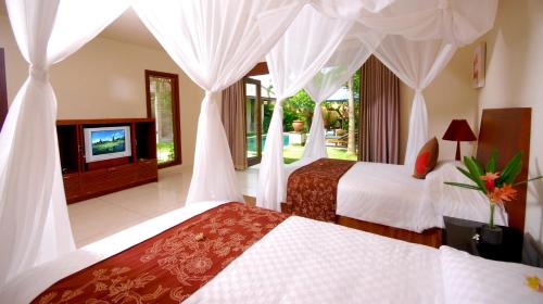a hotel room with two beds and a television at Nomad Hub Canggu Bali in Canggu