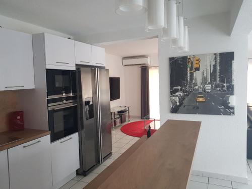 une cuisine avec des armoires blanches et des appareils en acier inoxydable dans l'établissement Appart ARCAIM, climatisé 90m2, 4 chambres, à 200m de la plage, à Argelès-sur-Mer