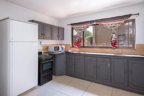 a kitchen with gray cabinets and a white refrigerator at Linden Guest House in Johannesburg