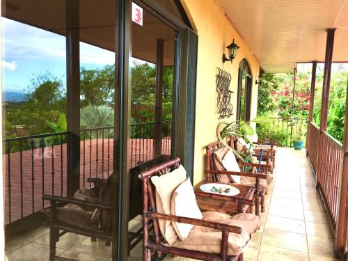 a porch with rocking chairs on a house at Hotel Vista Linda Montaña in Alajuela City