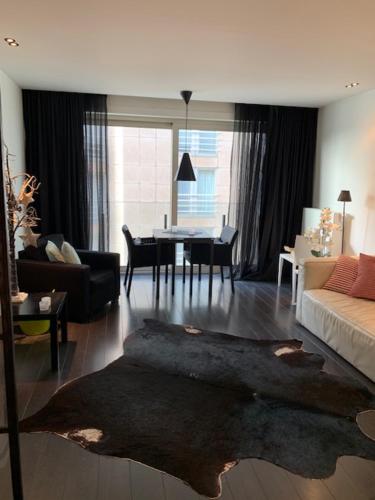 een woonkamer met een bank en een tafel bij Exclusief appartement in hartje Zoute, zonnig terras met zeezicht in Knokke-Heist