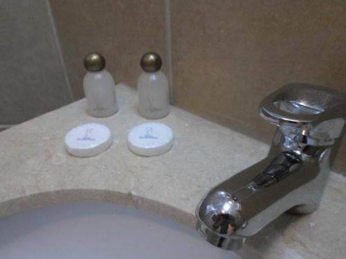 a bathroom sink with a faucet and two bottles at Hotel Del Marques in Vallenar