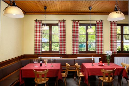 KNAUS Campingpark Bad Kissingen في باد كيسينغن: مطعم بطاولتين مع مفارش مائدة حمراء
