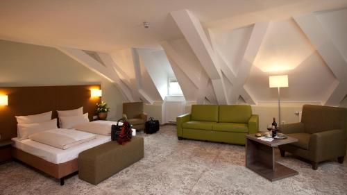 a bedroom with a bed and a couch and chairs at Hotel Jakob Regensburg in Regensburg
