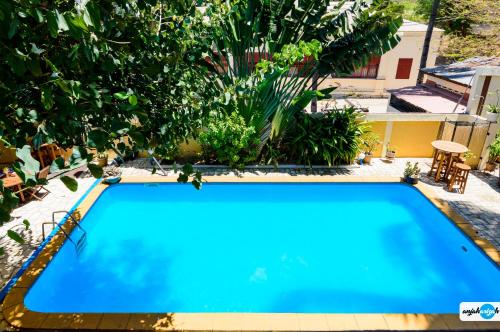 a blue swimming pool in a yard with plants at Hôtel Restaurant Coco Lodge Majunga in Mahajanga