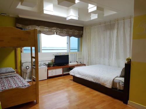 a bedroom with a bed and a television in it at Nice View Guesthouse in Seogwipo