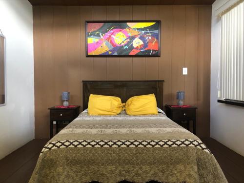 ein Schlafzimmer mit einem Bett mit gelben Kissen und einem Gemälde an der Wand in der Unterkunft Posada Cañaveral in Ujarrás