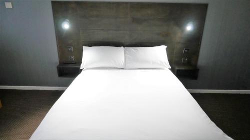 a bed with two white pillows in a room at Warrens Village Motel and Self Catering in Clevedon