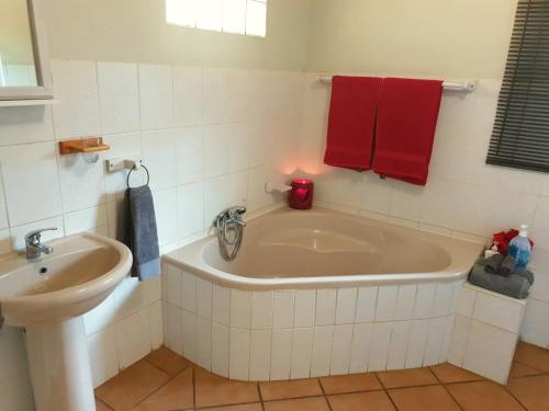 a bathroom with a tub and a sink and red towels at SnL 38 Hoep Hoep in Malelane
