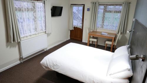 a bedroom with a bed and a table and windows at Warrens Village Motel and Self Catering in Clevedon