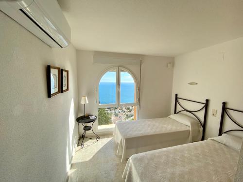 1 dormitorio con 2 camas y una ventana con vistas al océano en Duplex Vistamar X2154, en Benitachell