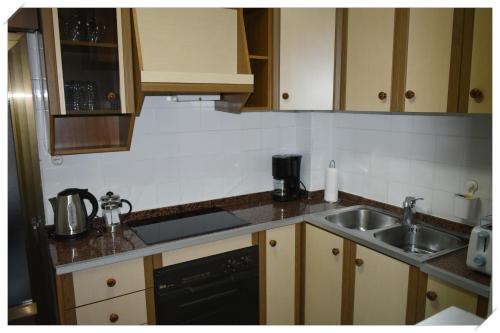 a kitchen with wooden cabinets and a sink and a dishwasher at Sol y mar a la playa in Puerto de Mazarrón