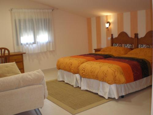 a bedroom with two beds and a chair at Hotel Rural La Consulta De Isar in Isar
