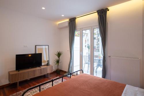 um quarto com uma cama, uma televisão e uma varanda em Phaedrus Living: City Centre Luxury Flat Mavromichali em Atenas