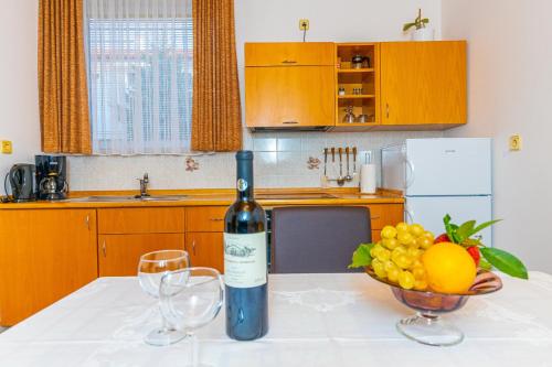 a bottle of wine sitting on a table with a bowl of fruit at Vacattio apartment 2 in Crikvenica