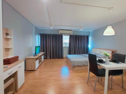 a room with a bed and a desk with a computer at Popular Condo เมืองทองธานี in Pak Kret