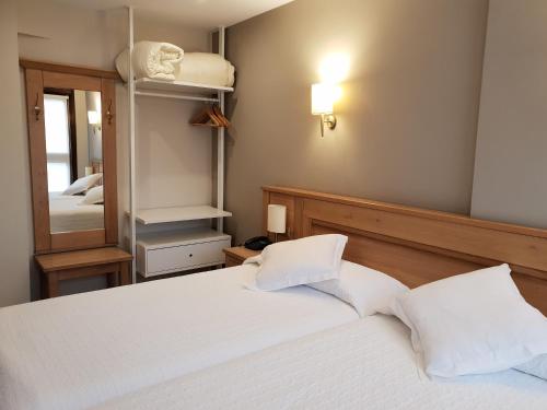 a bedroom with a white bed and a mirror at Hotel Alda A Boira in Jaca