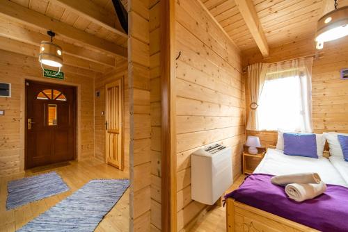 a bedroom with a bed in a wooden cabin at Eko domki MaMastra Szaflary in Szaflary