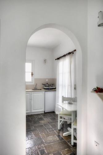 a kitchen with white cabinets and a table and a window at Aegean Village in Parikia