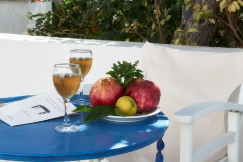 a table with two glasses of wine and a plate of fruit at Aegean Village in Parikia