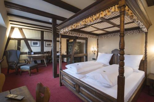 a bedroom with a four poster bed and a desk at Hotel Ochsen Post in Tiefenbronn