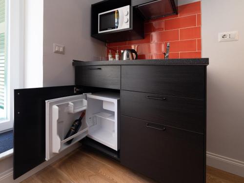 una cucina nera con forno a microonde e frigorifero aperto di Design Studio Flat with Terrace Next Toledo Metro Stop a Napoli