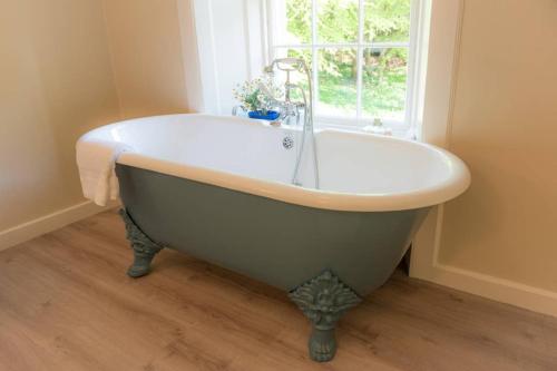 a white bath tub in a bathroom with a window at Quarry Gardens Lodge in Fochabers