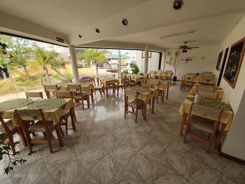 un ristorante con tavoli e sedie e una stanza con finestre di Hotel Reviens a Villa Gesell