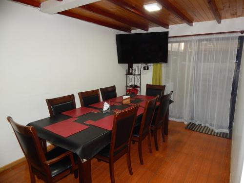 a dining room with a table and chairs and a television at Hostal Plaza Maule Express in Talca